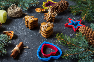 Christmas gingerbread cookies and fir tree and cones on dark stone background.