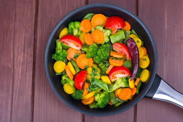 Carrots, broccoli, tomatoes  in  frying pan. Vegetarian menu