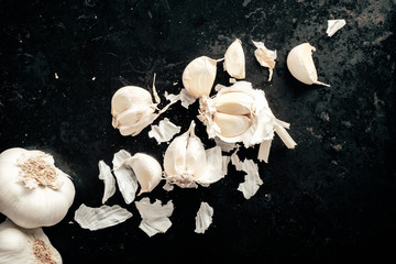 Raw garlic cloves and bulb on antique dark black background. Top view.