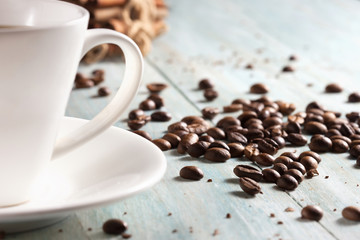 Coffee cup with coffee beans on wooden boards close-up