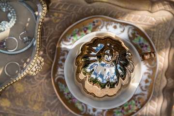 Golden table decoration idea - tray, mirror in gold frame, porcelain tea cup, jewelry box