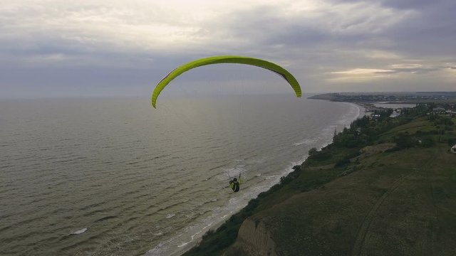 Paraplane, paraglider in the air aerial shot. Extreme man flies on a paraglider over a cliff near the sea. Extreme life.