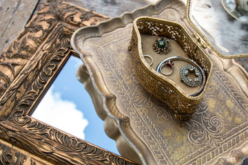 Golden table decoration idea - tray, mirror in gold frame, porcelain tea cup, jewelry box