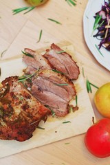 Marinated roast meat, seasoned green sprigs rosemary, cut into pieces on a wooden Board, close-up, selective focus. The view from the top.