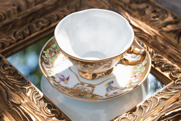 Golden table decoration idea - tray, mirror in gold frame, porcelain tea cup, jewelry box