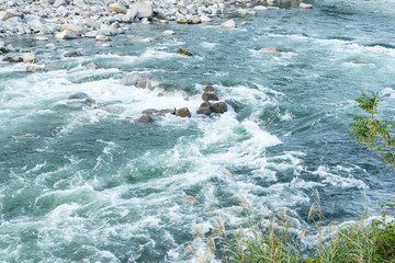 Strong and danger cold flowing blue river water and huge stone and rocks in autumn japan as adventure travel