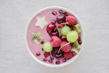 red pink and green smoothie bowl with cherry, melon, strawberry, raspberries and pomegranate , christmas fun food