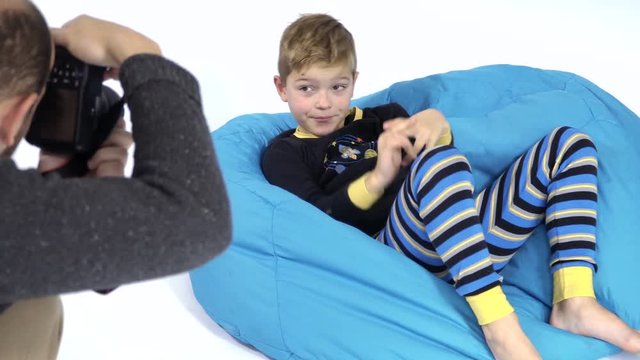 Photographer takes photo of cute little boy in pajamas at bean bag