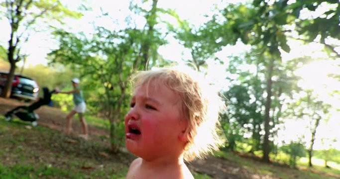 Candid real crying baby outdoors in 4k resolution. Casual natural crying infant toddler baby boy outside in the sunlight