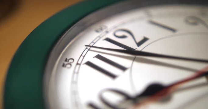 An extreme close up of the hands on a typical household wall clock. Rotating shot, shallow depth of field.  	