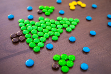 Christmas green pine tree made of colorful sweet chocolate round candies New year 2018 on a rustic wooden background . Holiday concept. Snow Moon and sky imitation