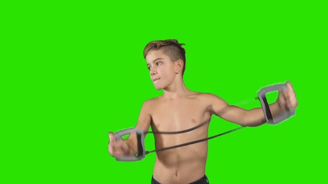 Little boy stretches elastic expander at green background