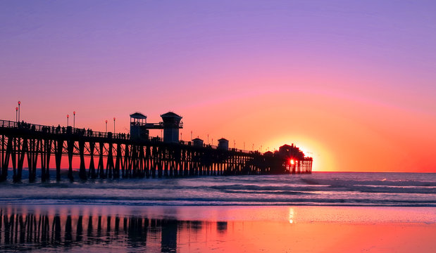 Beach at Sunset – colorful sunset with silhouette of boardwalk as ocean waves roll in