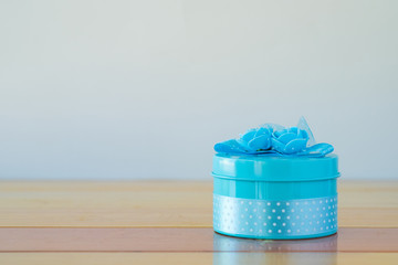 Round blue gift box with ribbon bow on wooden table with copy space for season or greeting and merry concept.
