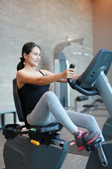 Fototapeta premium Pregnant woman exercise on the bicycle in sports hall.
