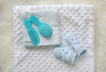 Obraz na płótnie Canvas Children's bath towel with brush comb and baby socks on white fur.