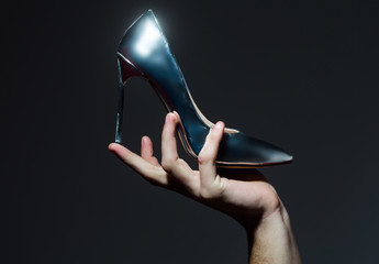 Shoe on high heel, stiletto, in hand on grey background