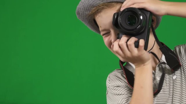 Little boy with relfex camera takes photo at chroma key background
