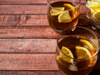 Glasses of cocktail with ice and lemon on wooden table close-up