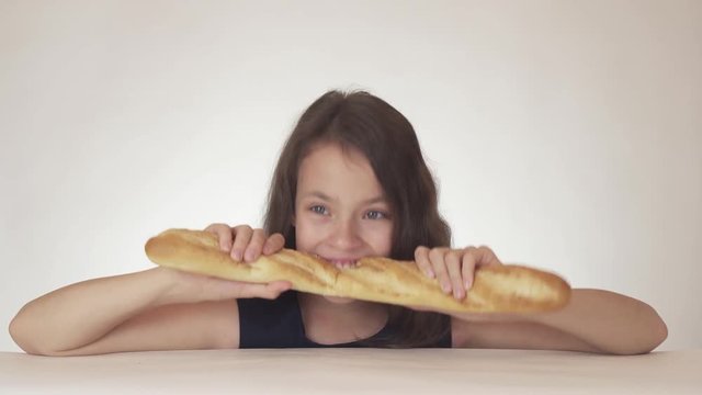 Beautiful happy girl teenager with greed and appetite eating a huge loaf of bread on white background stock footage video.