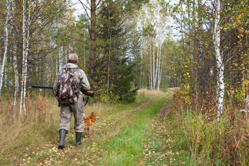 hunter with shotgun in the autumn forest
