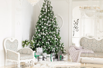 Luxury apartment decorated for christmas. Xmas tree with presents underneath in living room