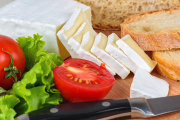 Breakfast from bread, cheese, tomatoes and all-over salad on a wooden table closeup.