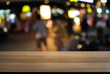 Empty wood table top and blur of night market background/selective focus .For montage product display.