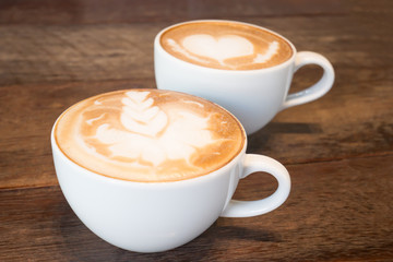 Two cups of coffee latte art on wooden table