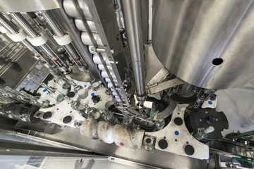 The mechanism of an automatic machine for filling and capping bottles.