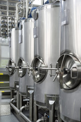 A lot of stainless steel tanks with large round hatches, modern beverage production.