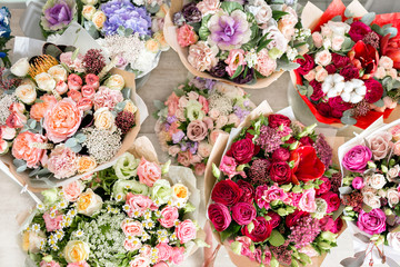 several beautiful bouquet of mixed flowers into a vase on wooden table. top view