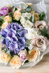 beautiful bouquet of mixed flowers into a vase on wooden table