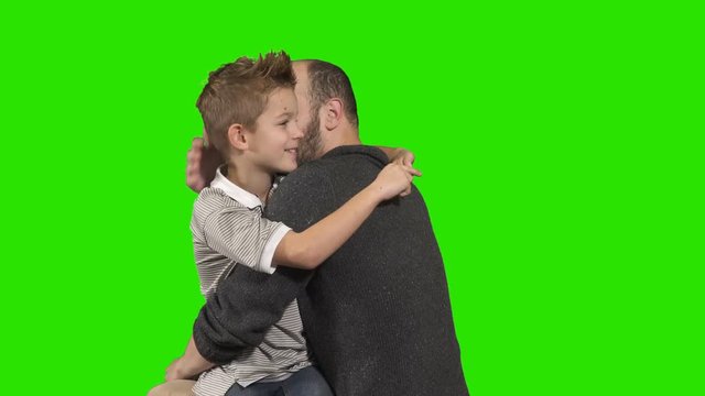 Little boy whispers secret on ear of his elder brother at green background