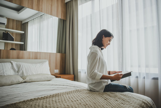 Beautiful woman reading a book sitting on the bed 