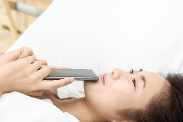 women sleep on bed in bedroom and holding smart phone