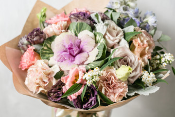 beautiful bouquet of mixed flowers into a vase on wooden table. copy space