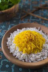 Rice cooked with saffron in a wooden bowl with fresh parsley for garnish
