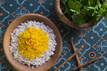 Rice cooked with saffron in a wooden bowl with fresh parsley for garnish
