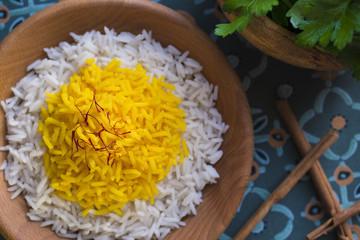 Rice cooked with saffron in a wooden bowl with fresh parsley for garnish