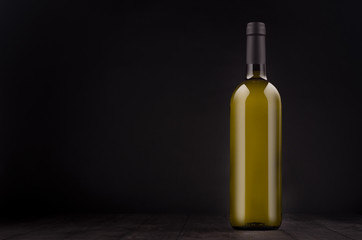 Green bottle of white wine mock up on elegant dark black wooden background, copy space. Template for portfolio, advertising, design, branding identity, cover magazine, bar and restaurant menu.