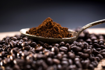 Coffee poured into an ancient antique silverware spoon. Around the spoons scattered coffee beans.