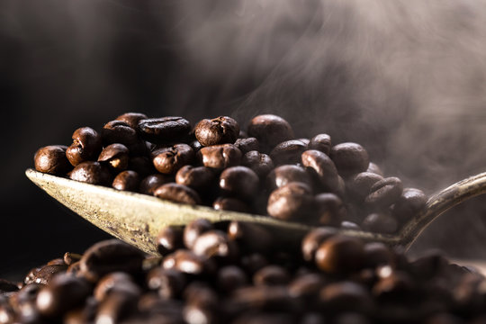 Roasted coffee poured into an old silver spoon.