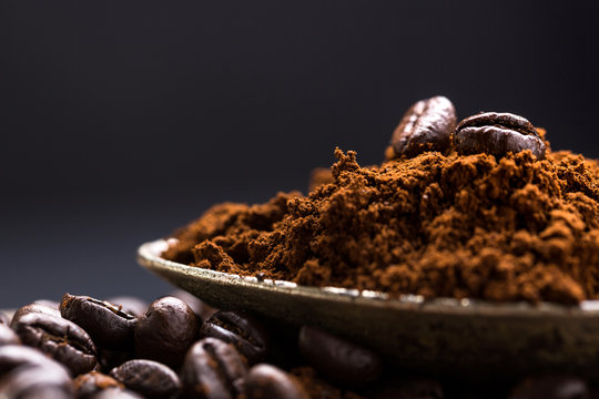 Coffee poured into an ancient antique silverware spoon. Around the spoons scattered coffee beans.