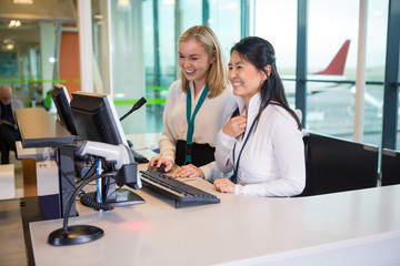 Smiling Receptionists Working At Desk In Airport