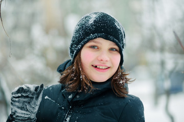 The girl looks out from behind the snow-covered branches.