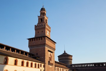 Fototapeta na wymiar Fragment of the castle wall with towers of Castello Sforzesco in the evening Milan, Italy