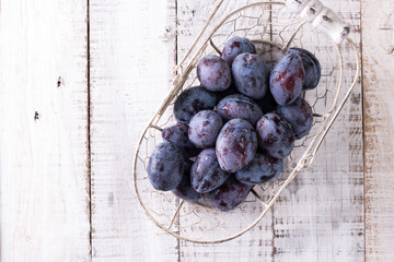 Plums. Blue and violet plums in the garden on wooden table.