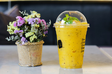 Yellow smoothie passion in plastic glass in a cafe