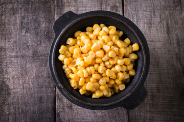 Sweet corn kernels in bowl on wooden table . Cooked canned yellow vegetable, vegetarian staple food.